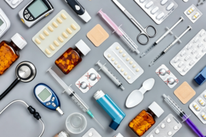 Various medical equipment, syringes, and pharmaceutical blister packaging arranged on a gray background.